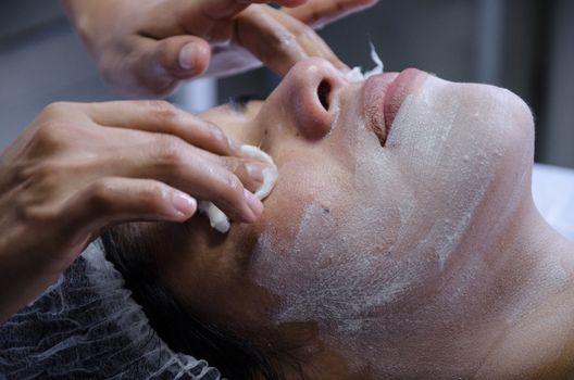 Cosmiatra performing facial cleansing on a patient