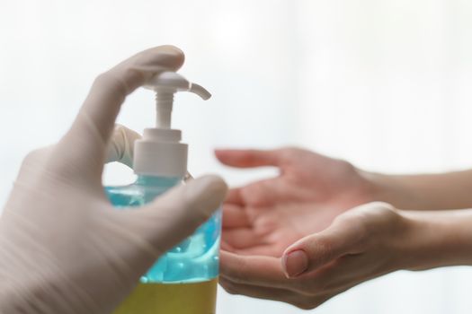 hands using wash hand sanitizer gel pump dispenser. transparent sanitizer in pump bottle, for killing germs, bacteria and virus.