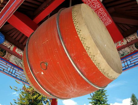 A large Chinese ceremonial drum suspended under a traditional roof
