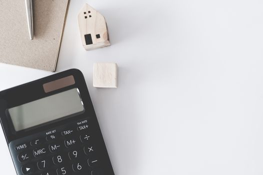 Top view of blank white copyspace with calculator, tiny home model, credit card and pen as frame background. Investing loan plan of money situation lifestyle concept.