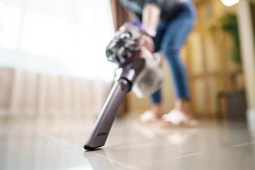 Woman use vacuum cleaner cleaning on floor.