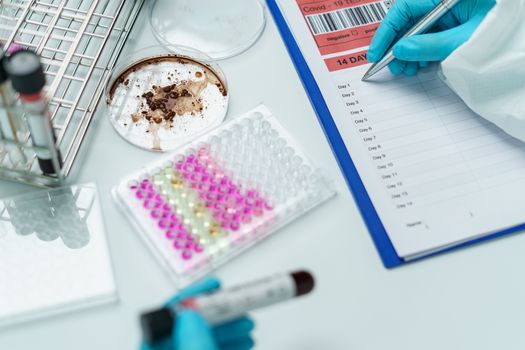 Scientist writing report information about blood test.Coronavirus testing process.