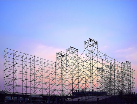 Complex scaffolding setup for a stage for an outdoor concert seen at sunset