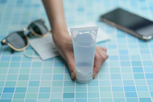 Hand with must have items- smart phone, protective face mask, glasses and sanitizer gel corona virus, or Covid-19 protection.