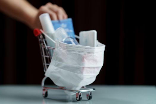 Hands pushing shopping cart and sanitizer products with protective face mask corona virus or Covid-19 protection.