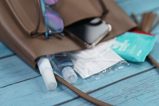 Hand bag with 2020 must have items smart phone, protective face mask, glasses and sanitizer gel corona virus or Covid-19 protection.