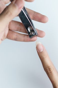 Man using nail clipper clipping her fingernails. white background