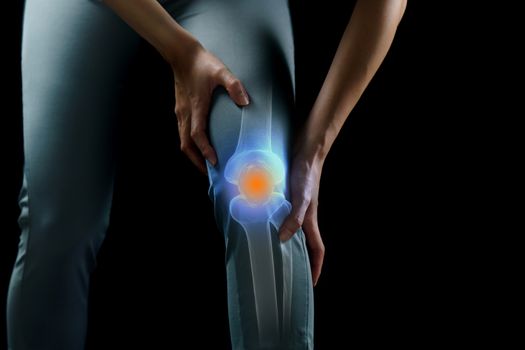 Woman holds her hands to the knee, pain in the knee highlighted in blue, medicine, massage concept.