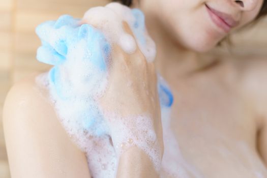 Woman washing her body with bath sponge.