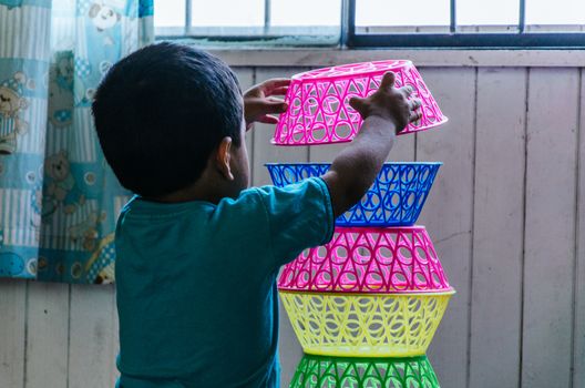 Boy playing to form a tower with plastic baskets