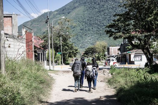 Girls backpacking walking among a path full of bushes and dirt