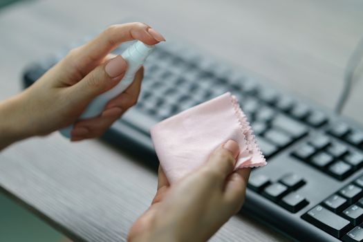 Woman hand desinfecting devices at home for prevent disease by sanitazing keybord, corona virus or Covid-19 protection.