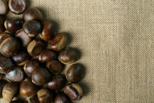 Roasted sweet chestnuts on rustic wooden table.