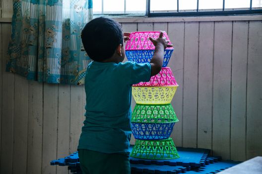 Boy playing to form a tower with plastic baskets