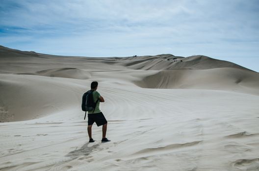 Backpacker man standing in front of the desert of Huacachina located in Ica - Peru