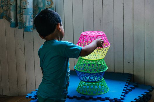 Boy playing to form a tower with plastic baskets