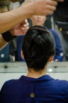 Stylist combing a woman in front of the mirror