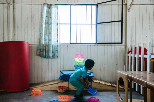 Boy playing to form a tower with plastic baskets