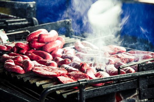 Many chorizos are cooked on a large grill
