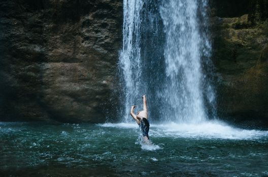 Man playing in the waterfall Velo de la Novia located in Chanchamayo - Peru, in the Yurinaki area