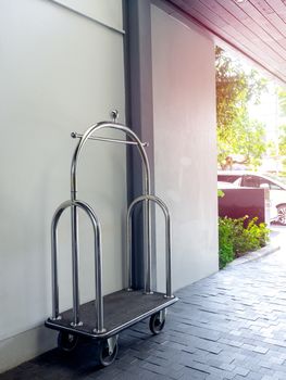 Empty silver chrome luxury hotel luggage trolley cart on a white wall in the hotel, vertical style.