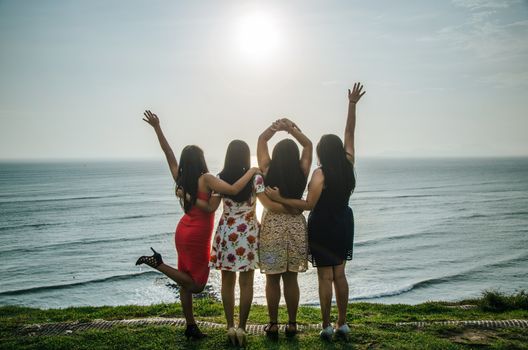 Girls in front of the sunset raising their hands