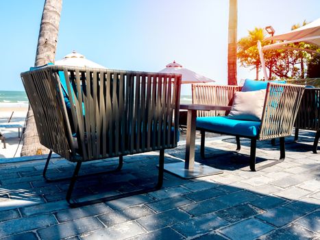 Modern chairs with round side table on balcony with sea view near the beach on blue sky background with sunlight in summer.