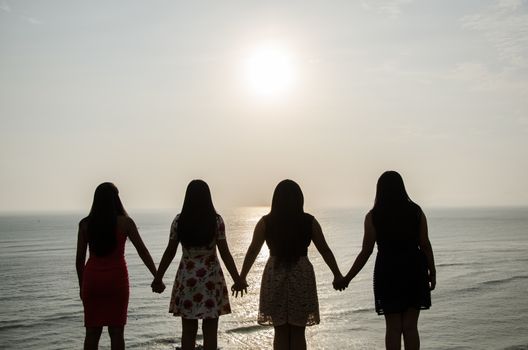 Girls in front of the sunset holding hands