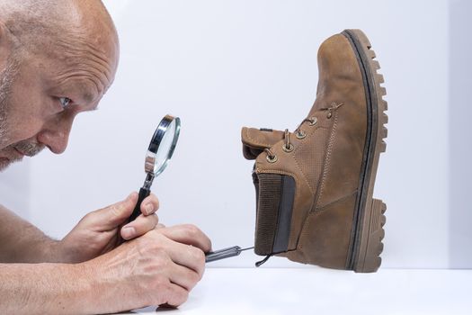 a man checks the inside of a shoe with a magnifying glass