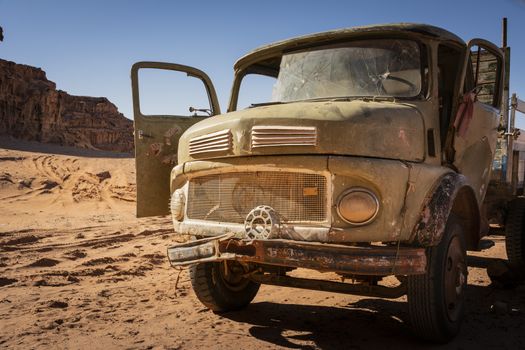 Wadi Rum, Jordan, March 2020: old rusty and worn-out broken vintage truck standing in the desert. Bullet holes in the windscreen. Abandoned vehicle.