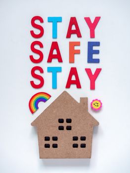 Stay safe concept. Colorful word "Stay Safe" with wooden home isolated on white background, stay at home, social media campaign for covid-19 or coronavirus pandemic prevention.