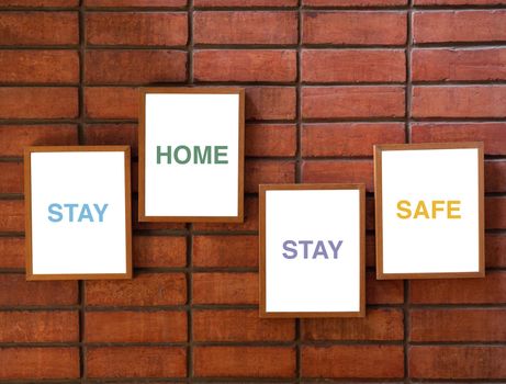 "Stay home stay safe" concept, text on white background in wooden frame on brick wall background.