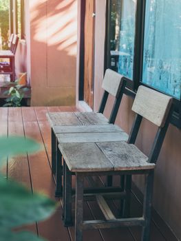 Old twin wooden chair on wooden terrace in front of room with glass window. Stay at home with relaxation concept, vertical style.