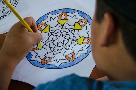 Child painting with colored pencil on a paper