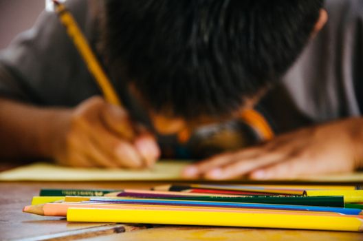 Child painting with colored pencil on a paper