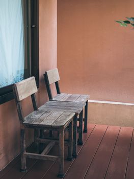 Old twin wooden chair on wooden terrace in front of room with glass window. Stay at home with relaxation concept, vertical style.