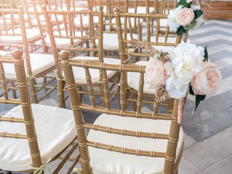 Wedding chairs decorate with beautiful flowers for wedding ceremony. Wedding set up with golden chairs.