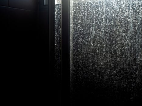 Dusty and dirty glass door. Water stain on sliding door in bathroom, dark background.