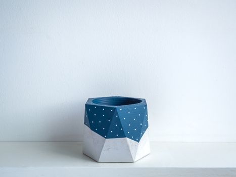 Cactus pot. Concrete pot. Empty blue painted modern geometric concrete planter on white wooden shelf isolated on white background.