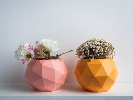 Cactus pot. Concrete pot. Pink and orange modern geometric concrete planters with blooming flower on white wooden shelf isolated on white background.