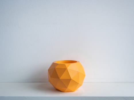 Cactus pot. Concrete pot. Empty orange modern geometric concrete planter on white wooden shelf isolated on white background.