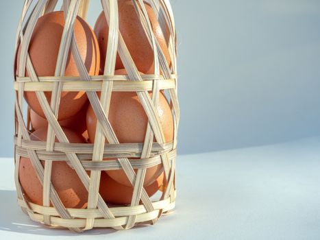 Close-up eggs in bamboo basket isolated on grey background with copy space.