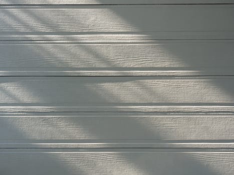 Soft white empty wooden surface background. Warm light and shadow on wood plank texture.