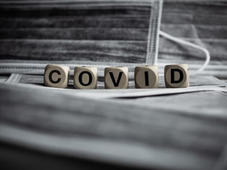 Coronavirus or Covid-19 concept. Wooden cubes text "COVID" on protective face mask background.