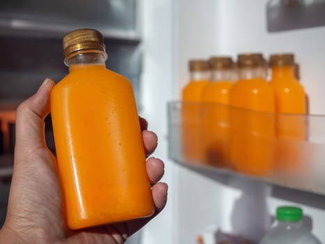 Orange juice iced cold in the bottles. hand holding square shape bottle with cold orange juice.
