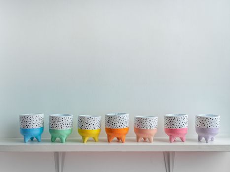 Cactus pot. Concrete pot. Empty colorful cute small concrete planters on white wooden shelf isolated on white background with copy space.