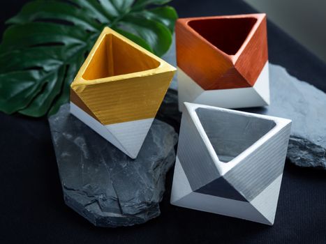 Cactus pot. Concrete pot. Gold, silver and copper painted geometric concrete planters on stone and dark background.