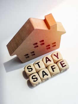 Stay safe concept. Word "Stay Safe" with wooden house isolated on white background, stay at home, social media campaign for covid-19 or coronavirus pandemic prevention.