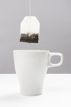 a filter bag of tea on top of a white tea cup