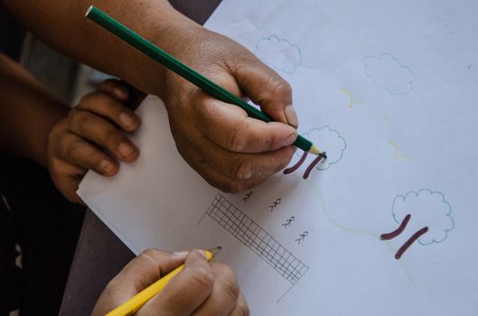 Children's hands drawing on a paper in the school